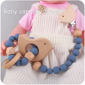 Detail of baby pacifier clip set featuring wooden bird teether and blue silicone beads