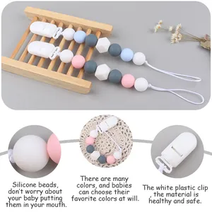 Detailed view of silicone pacifier clips with octagonal beads on a wooden tray