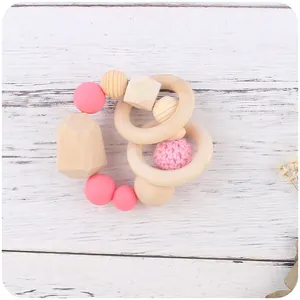 Baby Beißring aus Holz und Silikon mit rosa Häkelperlen auf rustikalem Hintergrund