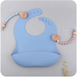 Detail view of baby silicone bib with adjustable neck buttons and a matching pacifier clip