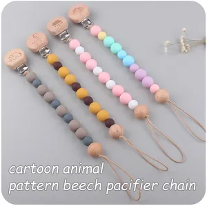 Détail des attaches-tétines en hêtre avec perles en silicone et motifs animaux gravés