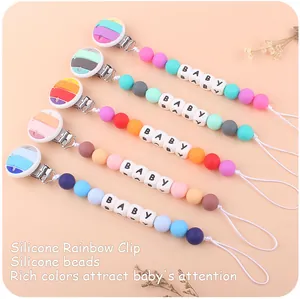 Detail of five colorful silicone pacifier clips with rainbow patterns and baby letter beads