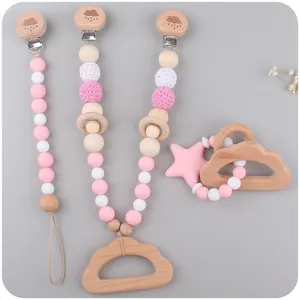 Détail de l'attache-tétine en silicone rose et set d'anneau de dentition nuage en hêtre