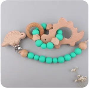 Detail view of dinosaur wooden teether set with silicone pacifier clip on grey background