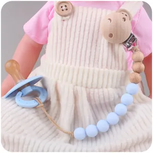Détail d'une attache-tétine en bois de hêtre et silicone bleu sur un vêtement bébé