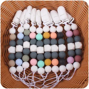 Silicone baby pacifier clips in various colors arranged in a woven basket