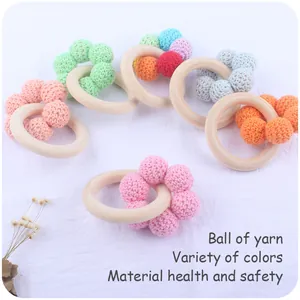 Detailed view of colorful handcrafted crochet cotton balls on natural wooden baby teethers