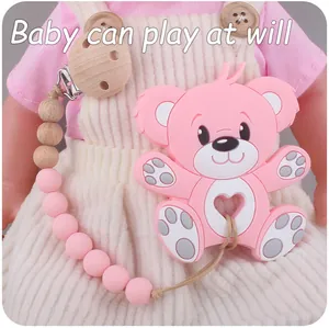 Pink bear silicone teether with wooden bead clip shown on a baby doll outfit