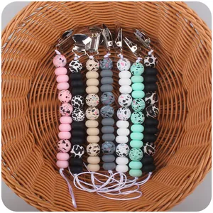Detail view of seven silicone pacifier clips with leopard and terrazzo bead patterns