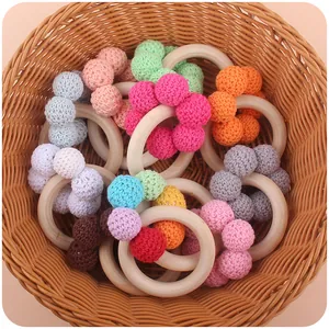 Close-up of wooden baby teething rings with colorful crochet beads in a wicker basket
