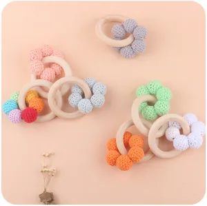 Detail of wooden baby teether rings with colorful crochet flower decorations for grasping