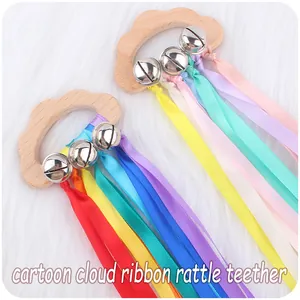 Macro shot of cloud-shaped beech wood teether with silver bells and rainbow ribbons