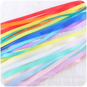 Close-up of colorful silk ribbons on soft white plush fabric for sensory baby toys