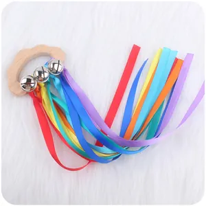 Close-up of wooden cloud teether toy with silver bells and colorful rainbow ribbons