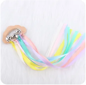 Detail of cloud-shaped beech wood rattle with silver bells and pastel silk ribbons