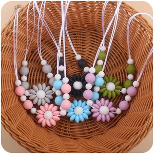Detailed view of colorful silicone daisy flower teething necklaces in a woven basket