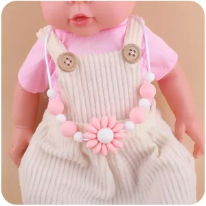 Detail of pink silicone flower pendant and beads worn by a baby doll model
