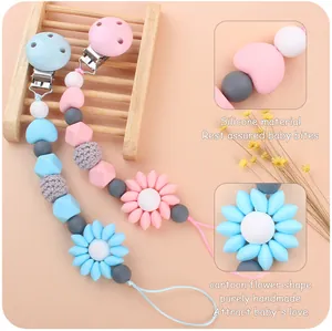 Detail of handmade silicone pacifier clips with flower beads in pink and blue colors