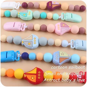 Close-up of silicone pacifier clips with colorful beads and cartoon sailboat designs