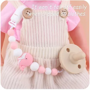 Close-up of silicone pacifier clip with pink whale bead on baby doll clothing