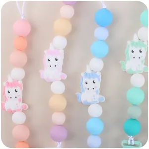Silicone baby pacifier clips with cartoon unicorn charms in pastel pink, yellow, blue, and green