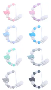 Close-up of silicone baby pacifier clips in various colors with cute whale designs
