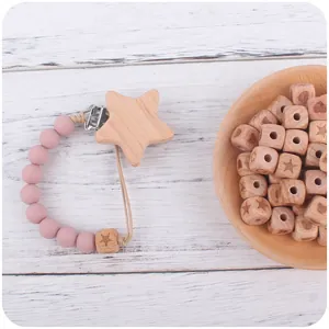 Natural beech wood star clip and silicone bead pacifier chain on white wooden desk