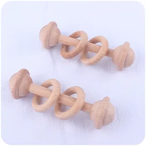 Vue détaillée de deux hochets en bois de hêtre naturel sur un tissu blanc texturé doux