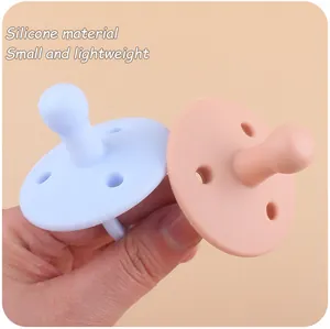 Detailopname van lichte siliconen fopspenen voor baby's in blauwe en roze kleuren in de hand