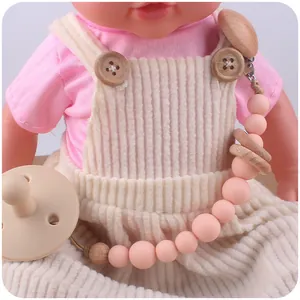 Nahaufnahme von Schnullerkette aus rosa Silikon und Buchenholz an Babykleidung