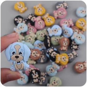 Main tenant une perle de dentition chien en silicone bleu avec des breloques colorées