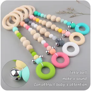 Detail of wooden baby teether rings with macaron silicone beads and a metal bell toy