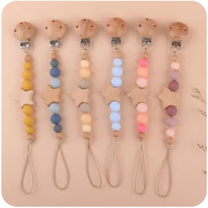 Dettaglio di sei catenelle portaciuccio colorate in legno di faggio con stelle per neonati