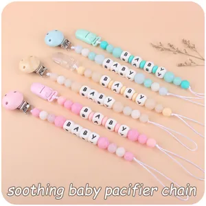 Close-up of colorful silicone pacifier clips with BABY letter beads and wooden accents
