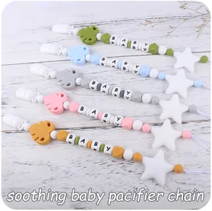 Set of 5 silicone pacifier clips with leaf beads and stars on a wood background
