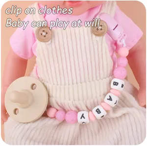 Detail of pink silicone pacifier clip with baby letter beads and a safety plastic clip