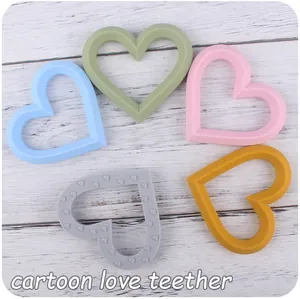 Detail view of heart-shaped silicone baby teethers in pastel macaron colors on wood