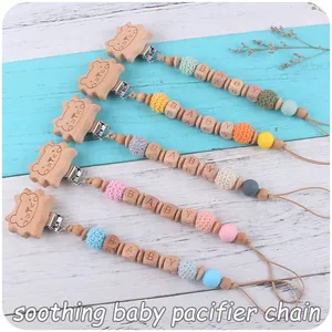 Détail d'attaches-tétines en bois avec clips lion et perles en crochet colorées