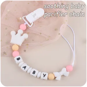 Detail of pink silicone pacifier chain with crown and BABY letter beads on mesh fabric