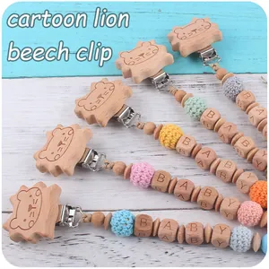 Détail d'attaches-tétines en bois pour bébé avec perles au crochet et motif lion