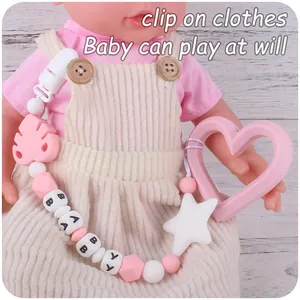 Detail of pink heart silicone teether and personalized beaded clip on a baby doll