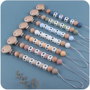 Detailed view of silicone and beech wood baby pacifier clips with BABY letter beads