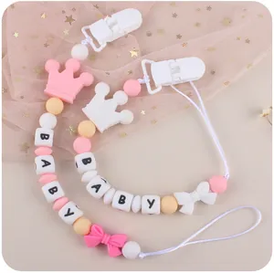 Detail of pink silicone pacifier clip with BABY letters and crown bead on starry mesh