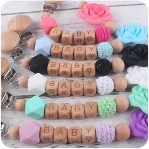 Détail d'attaches-tétines en bois avec perles de silicone colorées et motifs rose