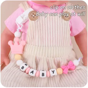 Detail of pink and yellow silicone baby pacifier clip with crown and BABY letter beads