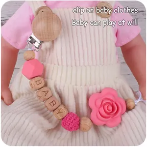 Détail de perles en silicone rose et clip en bois avec lettres BABY sur bébé