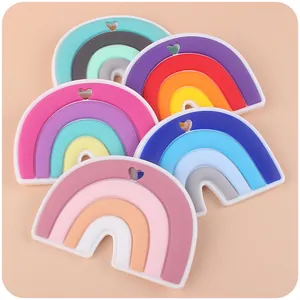 Five rainbow-shaped silicone baby teethers in assorted colors with a heart hanging hole