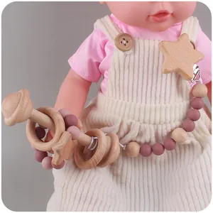Détail du hochet en bois et attache-tétine en silicone tenu par une poupée bébé