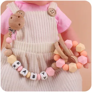 Detail of pink silicone beads and wooden baby pacifier clip with star-shaped teether toy