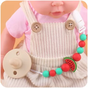 Close-up of silicone baby pacifier clip with watermelon beads on an infant doll